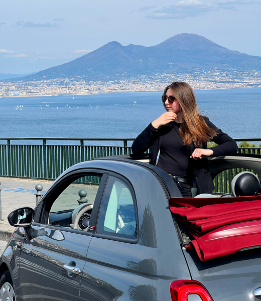 fiat 500 cabrio con ragazza che guarda il panorama dal tettuccio, sullo sfondo si vede il Vesuvio